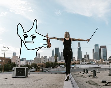 A huge cyborg llama head covers the skyline while a woman holding a violin walks into the distance